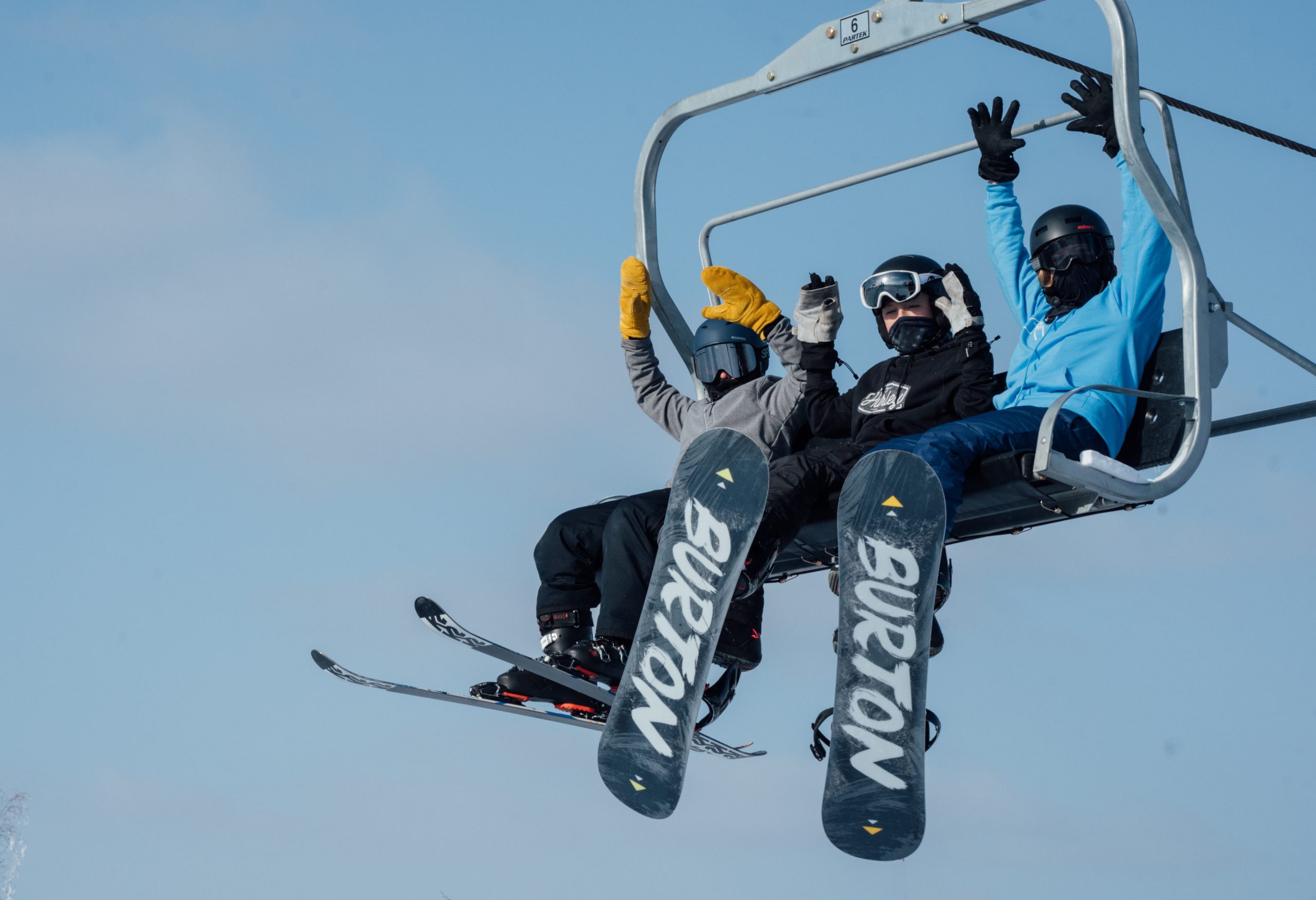 Photo of one skier and two snowboarders enjoying a chairlift ride at Trollhaugen